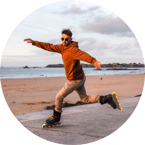 Mathieu Gervais en rollers sur la digue avec en fond la plage, la mer et le ciel de Saint Malo